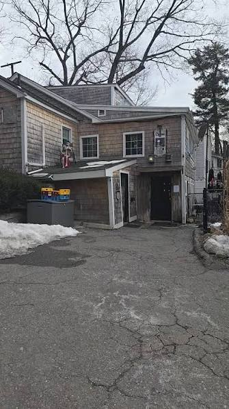 The Dudley Chateau from the parking lot: a grey shingled two-story building with an entrance under a small overhang, snow along the pavement.